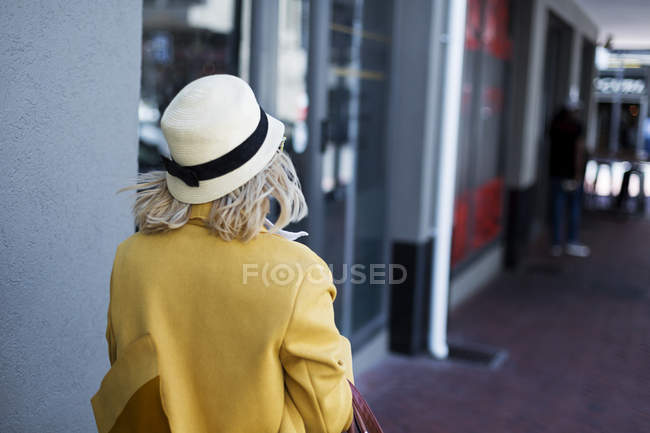 Задний вид женщины в шляпе, идущей по коридору — стоковое фото