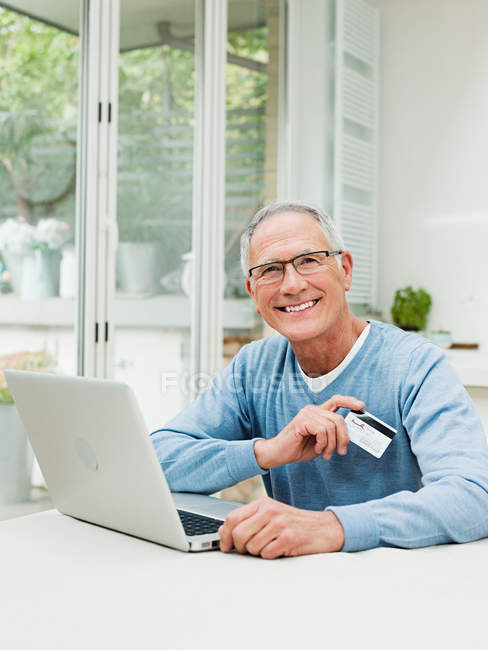 Uomo anziano che utilizza laptop con carta di credito — Foto stock