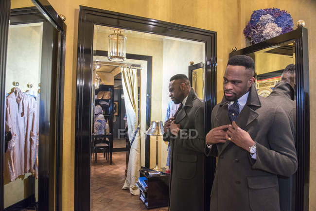 Jovem cliente masculino olhando no espelho na loja tradicional alfaiates — Fotografia de Stock