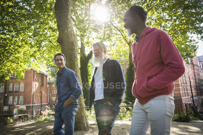 Tres hombres maduros caminando por la calle de la ciudad - foto de stock