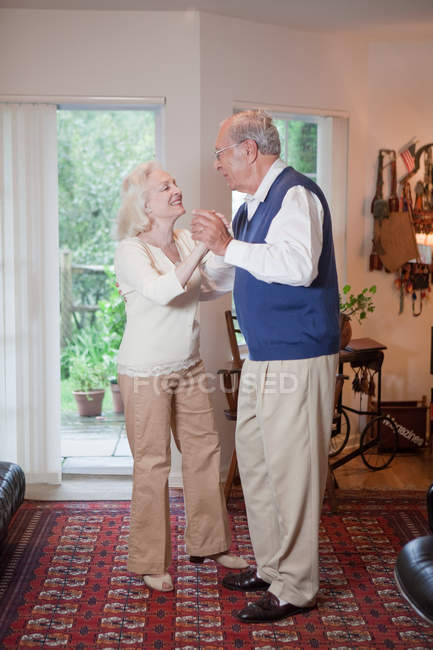 Casal sênior dançando juntos na sala de estar — Fotografia de Stock