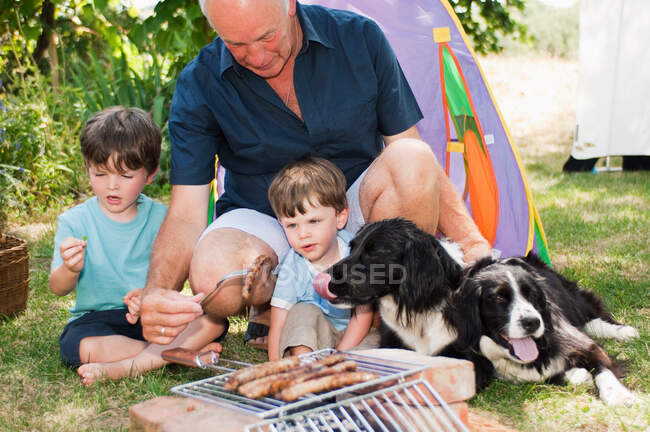 Grand-père et petits-fils faisant un barbecue — Photo de stock