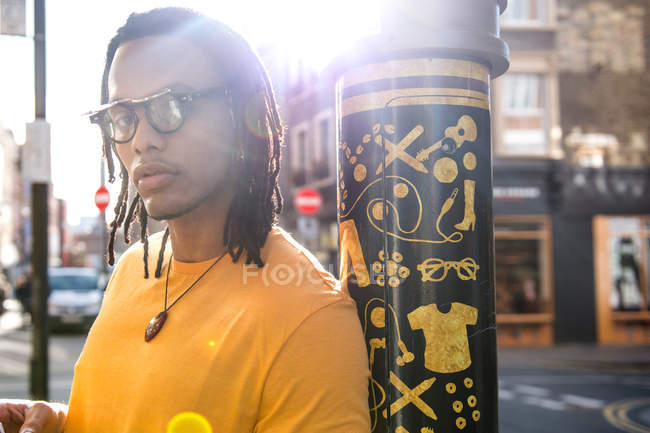 Портрет молодого человека на улице, прислоненного к фонарному столбу — стоковое фото