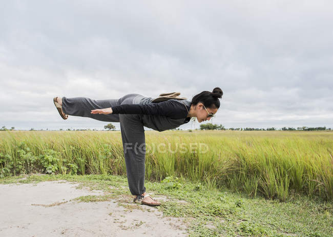 Side view of Young female tourist practicing yoga, Okavango Delta, Botswana, Africa — Stock Photo