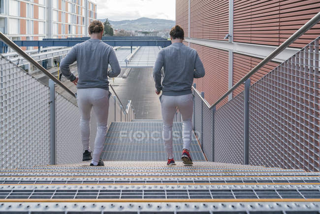 Rear view of twins running down on city stairway — Stock Photo
