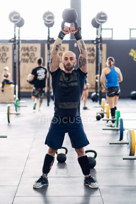 Man weightlifting with kettle bell in gym — Stock Photo