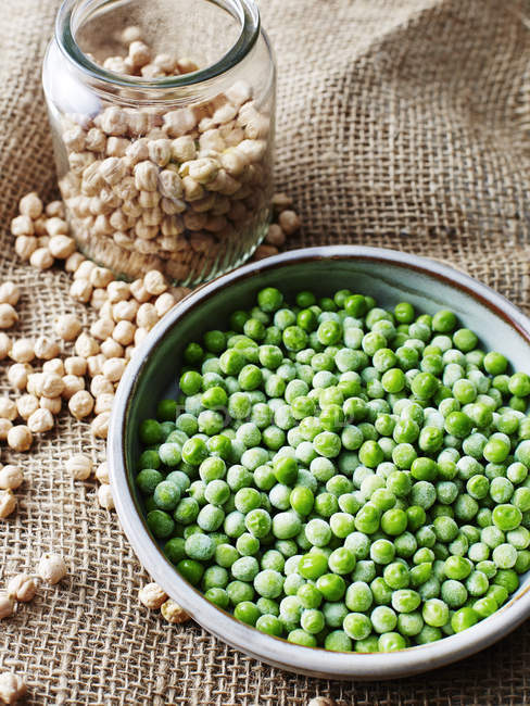 Still life with bowl of peas and jar of chickpeas — Stock Photo
