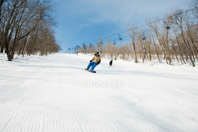 Duas pessoas snowboard na pista de esqui coberto de neve — Fotografia de Stock