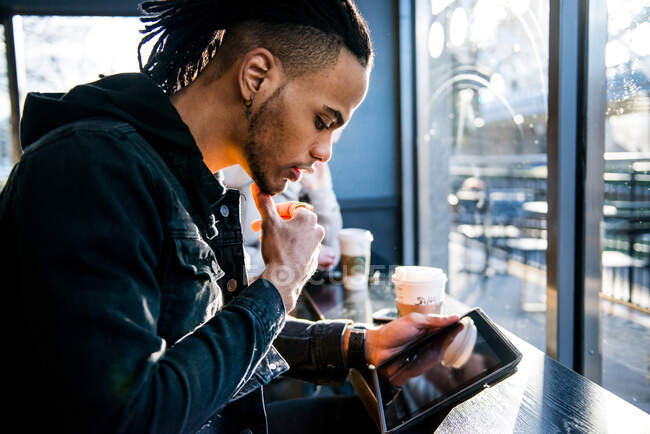 Jovem sentado no café, olhando para tablet digital, Londres, Inglaterra, Reino Unido — Fotografia de Stock