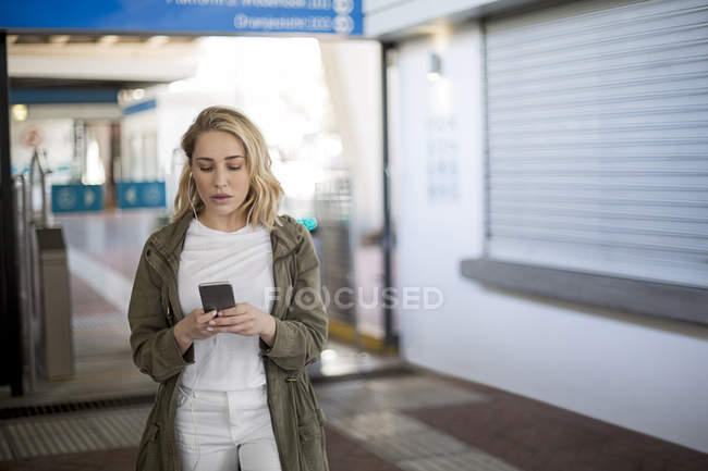 Mujer usando teléfono móvil por barrera de boletos, Ciudad del Cabo, Sudáfrica - foto de stock