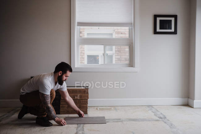 Vista laterale dell'uomo installazione di piastrelle del pavimento — Foto stock