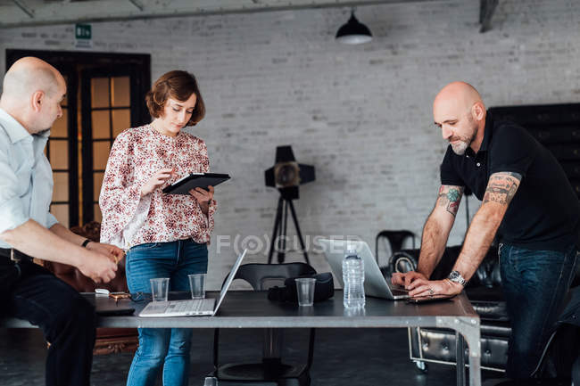 Colleagues at desk using digital tablet and laptops — Stock Photo