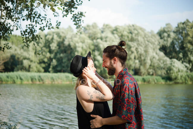 Casal jovem sorrindo um para o outro por lago, Toscana, Itália — Fotografia de Stock