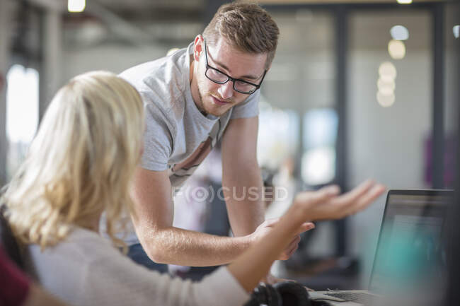 Male and female colleagues talking at office desk — Stock Photo