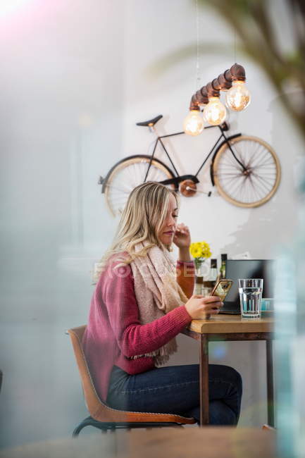 Vista lateral da mulher olhando para o smartphone no café — Fotografia de Stock