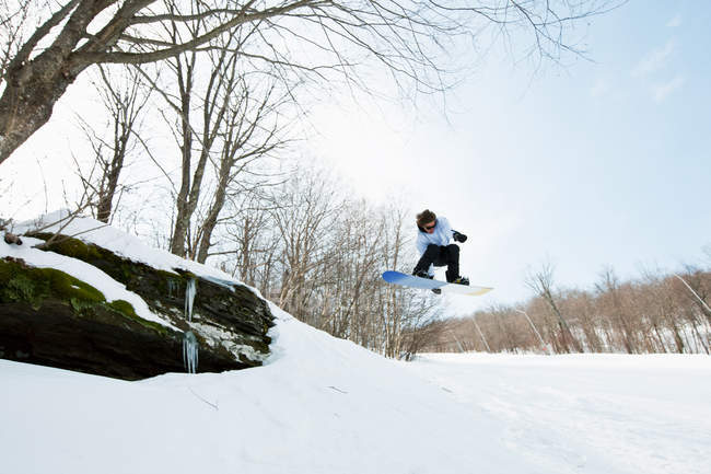 Vue à angle bas du snowboarder sautant de la colline — Photo de stock