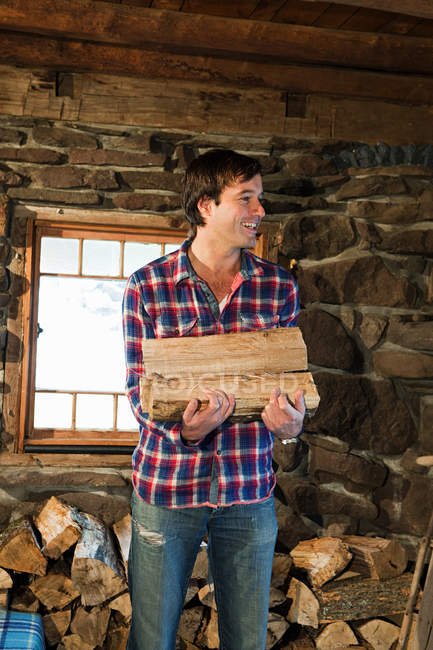 Retrato de hombre sosteniendo troncos en casa rústica - foto de stock