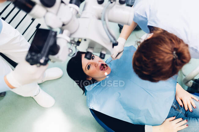 Dentist carrying out procedure on female patient, elevated view — Stock Photo