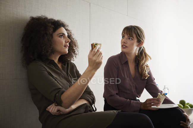Colleagues having lunch and talking in office — Stock Photo