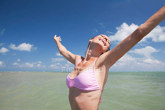 Felice giovane donna in mare a braccia aperte — Foto stock