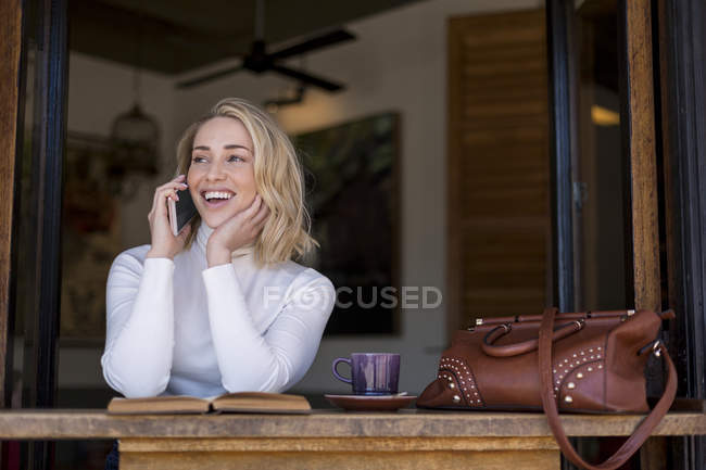 Woman talking on mobile phone at cafe, Cape Town, South Africa — Stock Photo