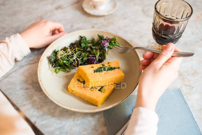 Mujer comiendo comida vegana en el restaurante - foto de stock