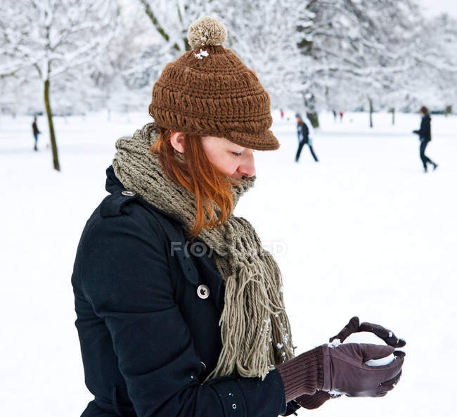 Woman making snowball in city park — Stock Photo
