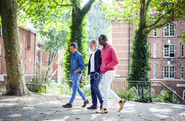 Três homens maduros andando na rua da cidade — Fotografia de Stock