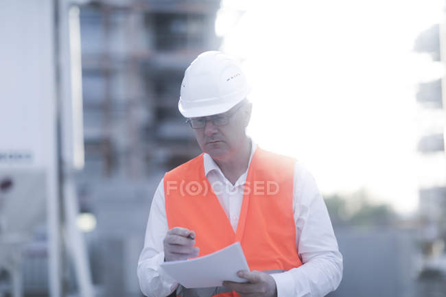 Erwachsener Bauarbeiter macht Notizen in Dokumenten — Stockfoto