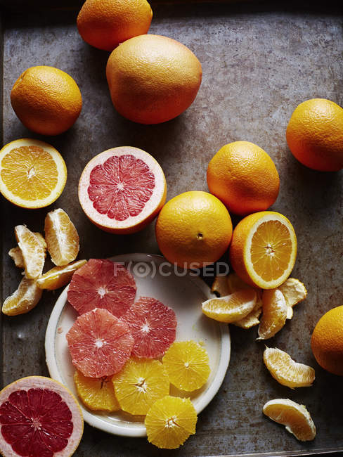 Bodegón con naranjas y pomelo, entero cortado a la mitad y en rodajas, vista aérea - foto de stock