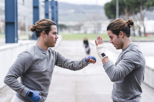 Боксёры-близнецы практикуют удары на открытом воздухе — стоковое фото