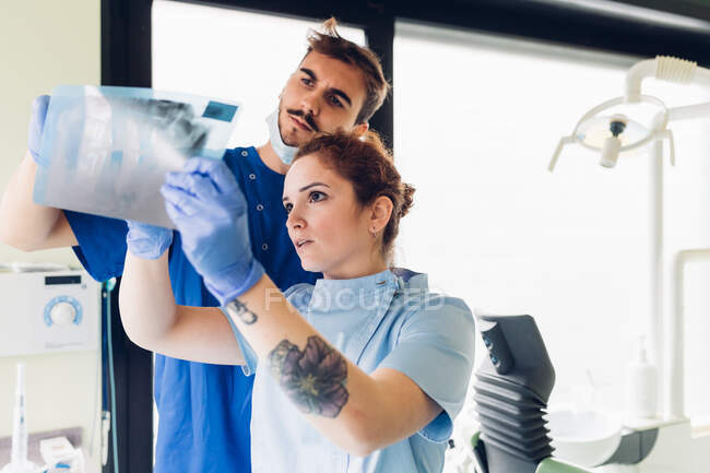 Dois dentistas em consultório odontológico, a ver radiografia dentária — Fotografia de Stock