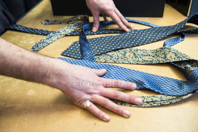Customer choosing a tie on tailors shop table, detail of hands — Stock Photo