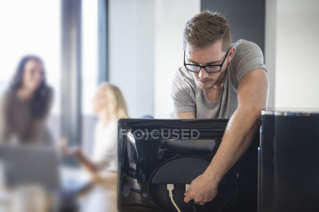 Компьютерный техник подключает кабель к компьютеру в офисе — стоковое фото