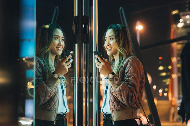 Женщина на улице держит смартфон по зданию — стоковое фото