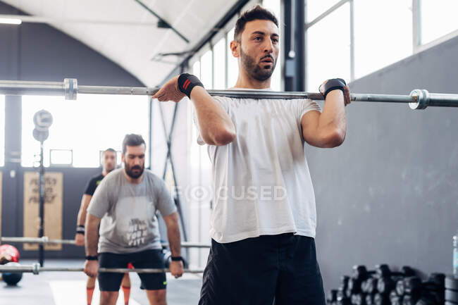 Levantamiento de pesas hombre con barra en el gimnasio - foto de stock