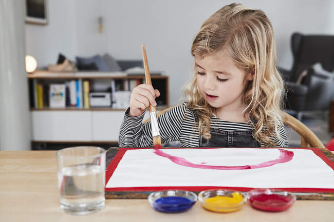 Молода дівчина малює картину за столом — стокове фото