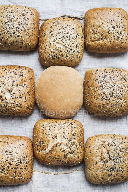 Вид зверху на мультизернові булочки з одним білим міні хлібом — стокове фото