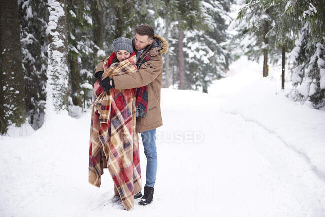 Молодая пара обнимается в снегу — стоковое фото