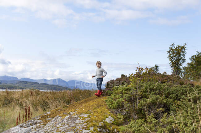 Boy playing on rock near fjord, Aure, More og Romsdal, Norvegia — Foto stock