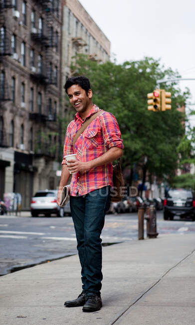Young man walking along city street, smiling — Stock Photo
