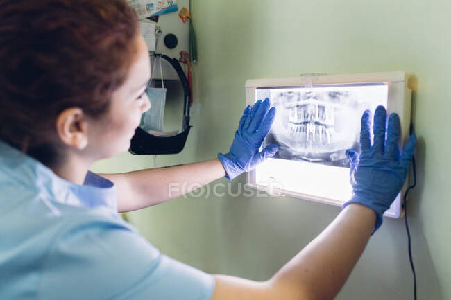 Female dentist looking at dental x-ray on lightbox — Stock Photo