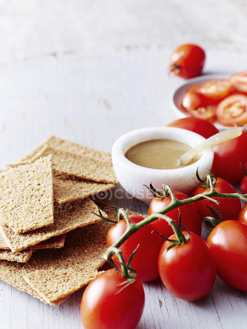 Still life with tahini, rye crackers and vine tomatoes — Stock Photo
