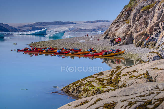 Turistas de aventura na praia do fiorde com fileiras de caiaques, Narsaq, Vestgronland, Groenlândia do Sul — Fotografia de Stock