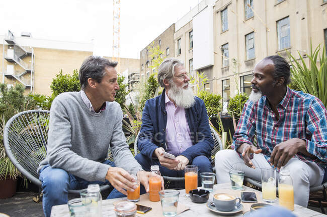 Friends chatting over drinks outdoors, London, UK — Stock Photo