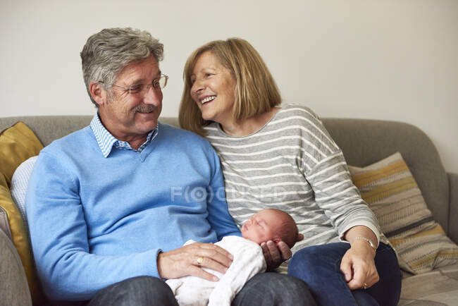 Grandparents on sofa with baby granddaughter — Stock Photo