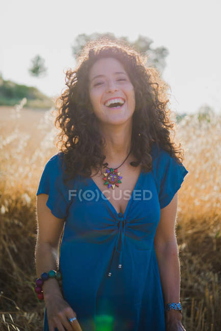 Porträt einer lockigen Frau, die auf dem Feld lacht — Stockfoto