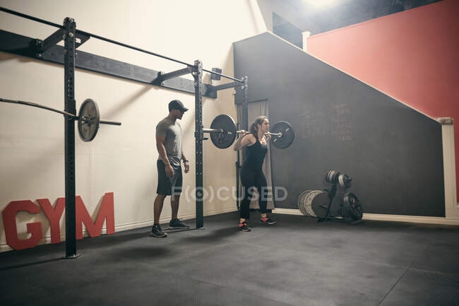 Mulher no ginásio levantamento de peso usando barra — Fotografia de Stock