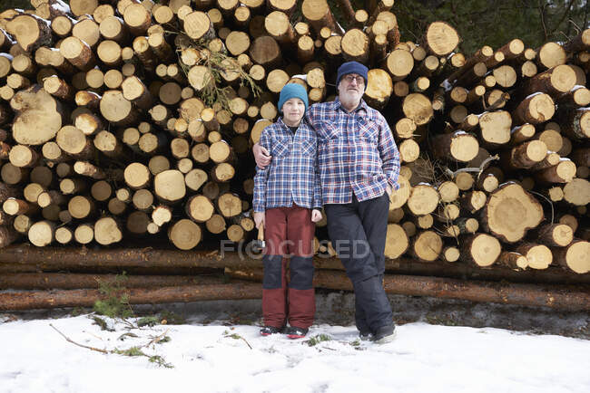 Retrato de padre e hijo, delante de un montón de troncos - foto de stock
