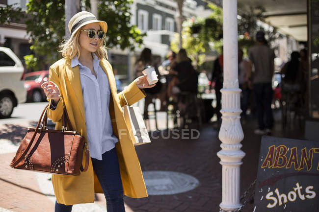 Woman with disposable cup passing restaurant, Cape Town, South Africa — Stock Photo
